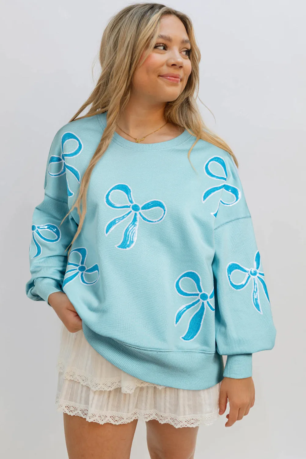 Beau Blue - Sweat-shirt surdimensionné à paillettes et nud papillon à épaules tombantes